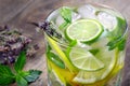 Glass of refreshing drink. glass of cold water with ice, thyme, mint and lemon on a wooden table. close up Royalty Free Stock Photo