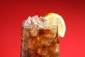 Glass of refreshing soda drink with ice cubes and lemon on red background, closeup Royalty Free Stock Photo