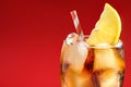 Glass of refreshing soda drink with ice cubes and lemon on red background, closeup. Space for text Royalty Free Stock Photo