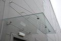 Glass roof above the entrance to the industrial building with metal cladding of the facade. thick-walled glass panel hangs above t Royalty Free Stock Photo