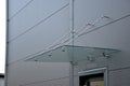 Glass roof above the entrance to the industrial building with metal cladding of the facade. thick-walled glass panel hangs above t Royalty Free Stock Photo