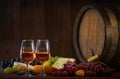 Glasses of rose wine cheeses grapesand barrel on brown wooden background Royalty Free Stock Photo