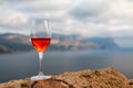 Glass of rose wine and with sea and beautiful sunset at background, close-up, horizontal composition. Summer evening relaxed mood