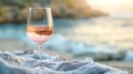 Glass of RosÃ© Wine on a Beach Towel Against a Blurry Seashore Background Royalty Free Stock Photo