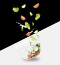 Glass salad bowl in flight with vegetables: tomato, cucumber and leaf salad. Isolated on white and black background. healthy diet Royalty Free Stock Photo