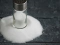 Glass salt shaker on the pile of salt finely on a wooden table. Royalty Free Stock Photo