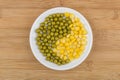 Glass saucer with green peas and sweet corn on table Royalty Free Stock Photo