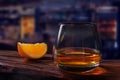 Glass of scotch whiskey and orange slice wood rustic table dark bar background Royalty Free Stock Photo