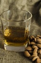 Glass of scotch whiskey on wool sack with almond seeds