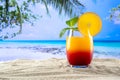 A glass with a sex drink on the beach on the sand in the background picture of a palm tree and the sea Royalty Free Stock Photo