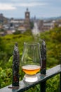 Glass of single malt scotch whisky and view from Calton hill to park and old parts of Edinburgh city in rainy day, Scotland, UK Royalty Free Stock Photo