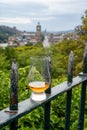Glass of single malt scotch whisky and view from Calton hill to park and old parts of Edinburgh city in rainy day, Scotland, UK Royalty Free Stock Photo