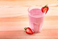 Glass of smoothie with ripe and fresh strawberries and organic milk on a light brown wooden table. Milkshake with strawberries. Royalty Free Stock Photo