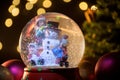 Glass snow globe with a Christmas tree and lights in the background Royalty Free Stock Photo