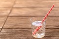 Glass of soda water with red white striped straw on wooden table. Refreshing non-alcoholic drink for hot summer days Royalty Free Stock Photo