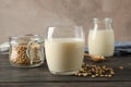 Glass of soy milk, soybeans seeds on spoon, napkin on wooden background