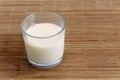 Glass of soya milk with froth on bamboo mat.