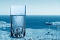 Glass of sparkling pure water against the sea background