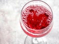 Glass of sparkling red wine showing tiny bubbles on grey background Royalty Free Stock Photo
