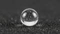 Glass sphere rests on a black textured surface resembling fine sand Royalty Free Stock Photo