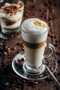 A glass of spicy latte with whipped cream and cinnamon, standing on a brown board. Coffee beans. Dark background Royalty Free Stock Photo