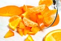 A glass of spilled orange fruit, cut into chunks, has fallen on its side