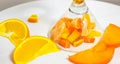 A glass of spilled orange fruit, cut into chunks, has fallen on its side