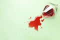 Glass with spilled red wine on light green background, top view. Space for text Royalty Free Stock Photo