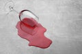Glass with spilled red wine on light grey surface. Space for text Royalty Free Stock Photo