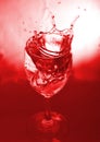 Glass with splash on red background