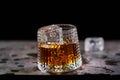 Glass of splashing whiskey with icecube on stone table, on black background