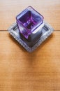 Glass square candle holder on a metal tray on a wooden background