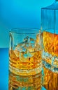 A glass and square crystal decanter with scotch whiskey or brandy in the background on a blue gradient background with reflection Royalty Free Stock Photo