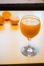 A glass of squeezed orange juice closeup, fresh and juicy oranges on a bright yellow and white background. Royalty Free Stock Photo