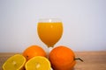 A glass of squeezed orange juice closeup, fresh and juicy oranges and lemon on a wooden table. Royalty Free Stock Photo