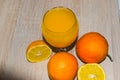 A glass of squeezed orange juice closeup, fresh and juicy oranges and lemon on a wooden table. Royalty Free Stock Photo