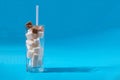 Glass with straw full of sugar and cubes on blue background
