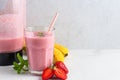 Glass of strawberry and banana smoothie with fresh juicy fruits and blender for making healthy summer drink Royalty Free Stock Photo