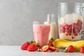 Glass strawberry and banana smoothie or milkshake with fresh juicy ingredients in blender for making healthy drink Royalty Free Stock Photo