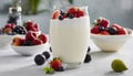 A glass of strawberry and blueberry yogurt with a bowl of fruit