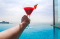 A glass of strawberry cocktail in female hands. Swimming pool Royalty Free Stock Photo