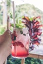 Glass of strawberry juice with soda in man hand. Tropical cafe background. Bali island. Royalty Free Stock Photo