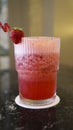 A glass of strawberry juice at the table with a fancy straw