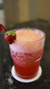 A glass of strawberry juice at the table with a fancy straw