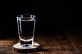 Glass of strong distilled alcoholic drink, with space for text, black background. Image for pug or bar