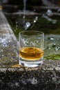 Glass of strong scotch single malt whisky served on old stone reservoir for water from mountain spring