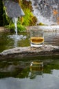 Glass of strong scotch single malt whisky served on old stone reservoir for water from mountain spring