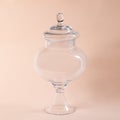 Glass sweets jar on a beige background