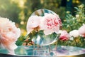 Glass table with mirror on blurred summer garden background with peonies