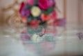 Glass table . Wedding rings next to a red flower bouquet selective focuse . Bride and groom with Engagement gold rings put on the Royalty Free Stock Photo